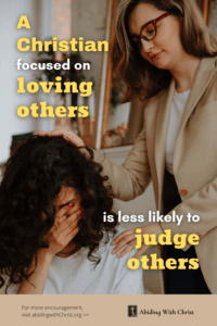 Link to Pinterest pin image of a woman comforting another woman who is crying with text that reads "A Christian focused on loving others is less likely to judge others". 