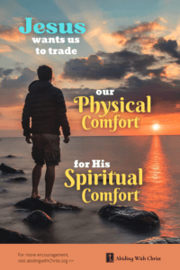 Link to Pinterest pin image of man standing on a rock in shallow sea, looking at a sunset, with text that reads "Jesus wants us to trade our physical comfort for His spiritual comfort".