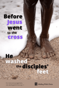 Link to Pinterest pin image of man standing at edge of sea, with sand on his feet and toes with text that reads "Before Jesus went to the cross, He washed the disciples' feet". 