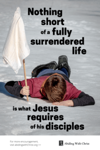 Link to a Pinterest pin image of a boy laying face down in the snow holding a white flag with text that says "Nothing short of a fully surrendered life is what Jesus requires of His disciples". 