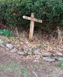 Small wooden cross in yard with He Lives engraved across it