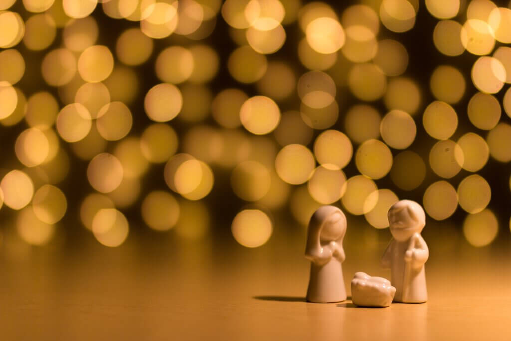 simple, tiny wooden nativity with Jesus, Mary and Joseph with soft lights in background for post why was Jesus born as a human?