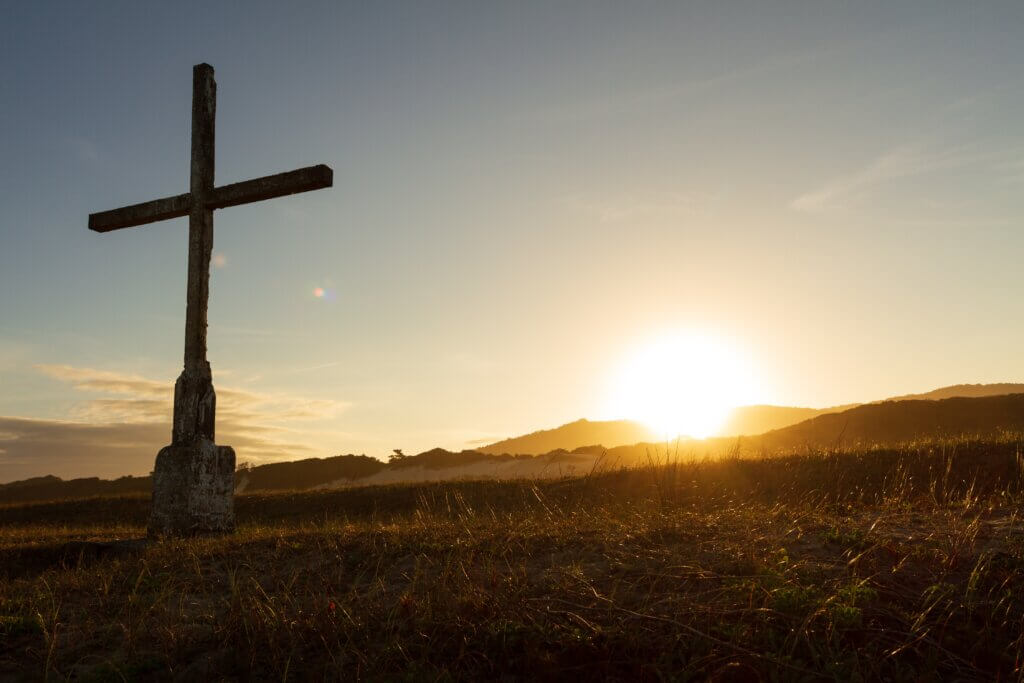 A simple wooden cross in a field facing the sunrise is a reminder that Jesus is the once for all sacrifice.